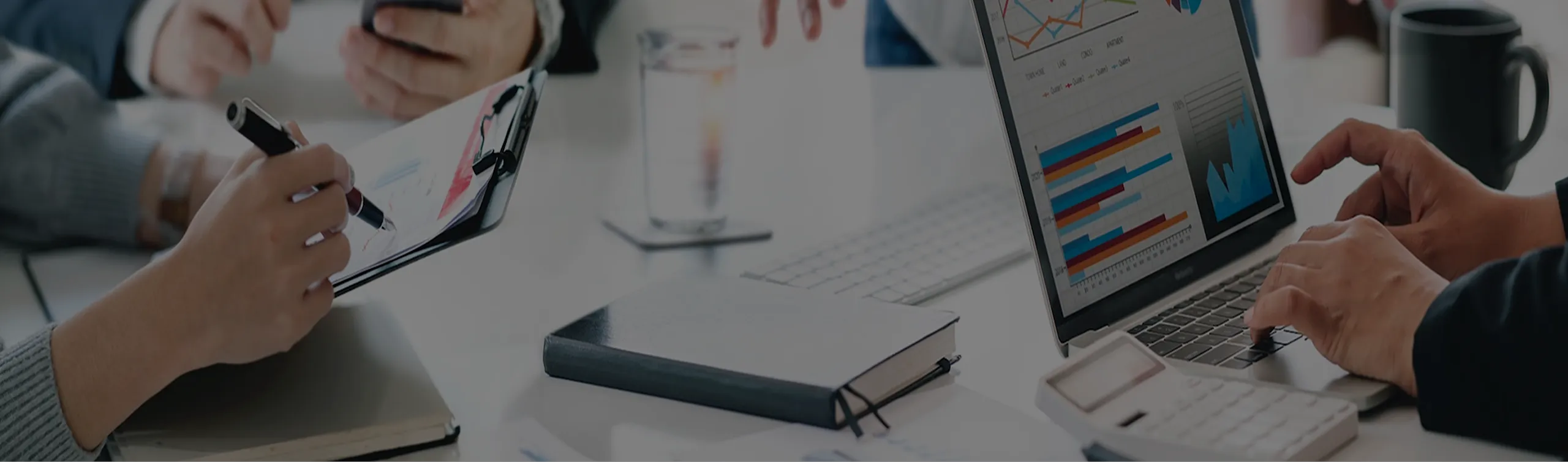 分析グラフやPC・資料が並ぶデスク風景