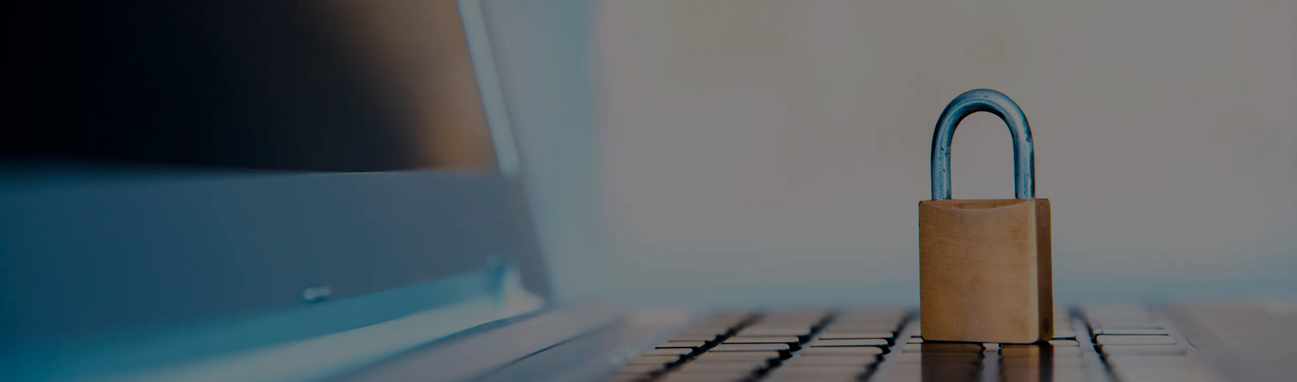 ノートパソコンの上に置かれた南京錠。厳格な個人情報保護体制と情報セキュリティ管理のイメージ