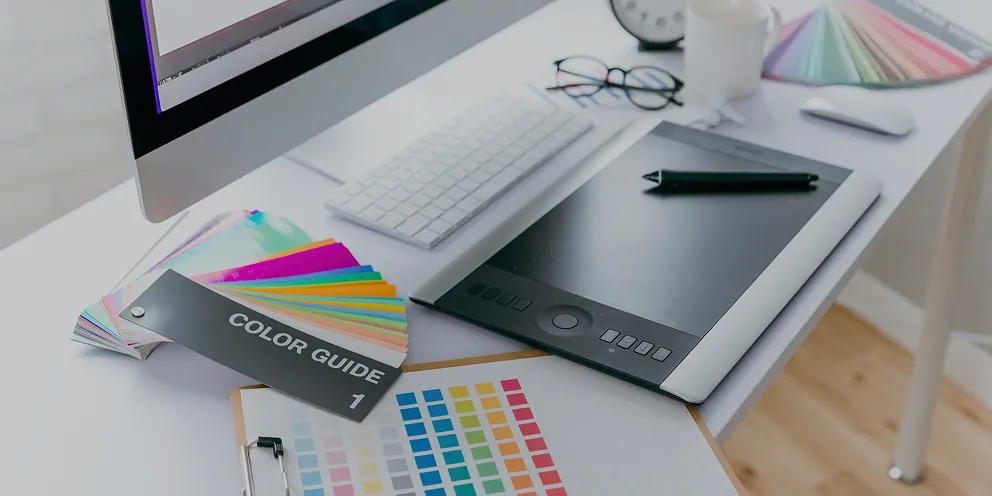 カラーガイドやペンタブレットが置かれたクリエイティブ・デザインの制作デスク