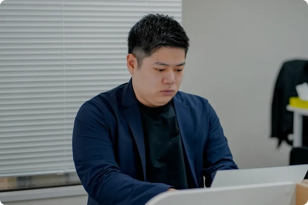 オフィスで真剣な表情でPCに向かい、データ分析や戦略立案に取り組む社員