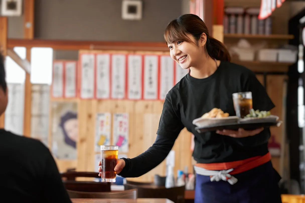 多店舗の給与業務を集約し、確認中心の運用へとシフトした飲食業の接客の様子